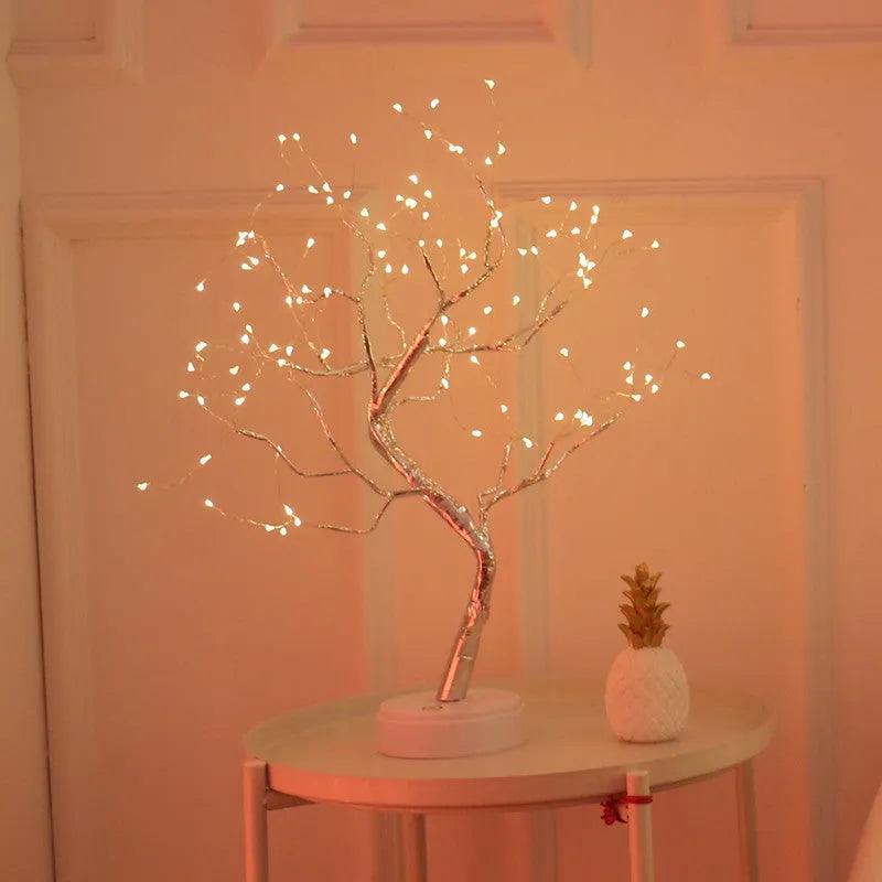 🎄 PearlGlow™ LED Christmas Tree Light with warm white LEDs on silver branches, placed on a side table for soft ambient lighting in any room.